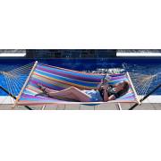 Woman lying in the multi colour spreader bar hammock beside a pool