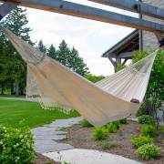 Beige crochet fringe hammock hung from a pergola beside a garden path