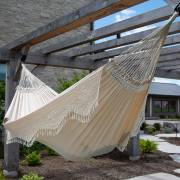Side view of the beige crochet fringe hammock hung from a pergola post