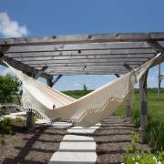 Beige crochet fringe hammock hung from a timber pergola