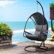 Black wicker egg chair on a timber deck beside the sea