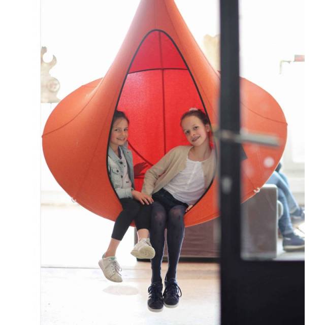 Two girls sitting in an orange Cacoon single indoors