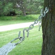 Chain and S-hook joining a rope hammock to a hook screwed into a tree