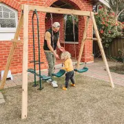 Adult helping a toddler at the glider of the timber swing set