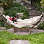 Woman relaxing in the beige fringe hammock on its wood arc stand on a lawn