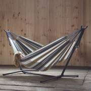 Beige and grey striped hammock on its steel stand against a timber wall