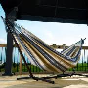 Beige and grey striped hammock on its steel stand on a deck