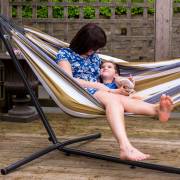 Mother and child lying in the beige and grey striped hammock on its steel stand