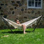 Woman sitting in the beige fringe hammock on its steel stand on a lawn