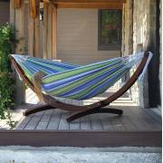 Blue and green striped hammock on its wood arc stand on a timber deck