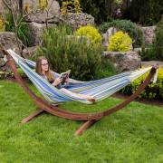 Woman reading in the blue and green striped hammock on its wood arc stand in a garden