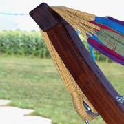 Close up of the end of the dark wood arc stand with the hammock strings looped over it