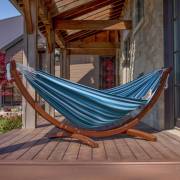 Mixed blues hammock on its wood arc stand on a timber deck