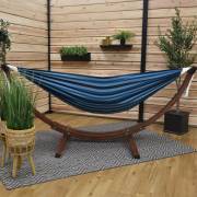 Mixed blues hammock on its wood arc stand on a covered patio with a rug