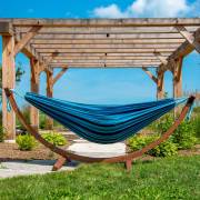 Mixed blues hammock on its wood arc stand under a pergola on a lawn