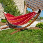Red and orange hammock on its wood arc stand in a garden