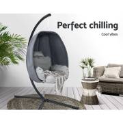 Grey egg chair on its stand on a timber deck beside a wicker lounge and side table