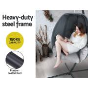 Woman reading a book curled up in the grey egg chair, with the 150kg capacity and powder coated steel frame noted