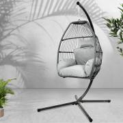 Grey open weave egg chair on its stand in a room with plants