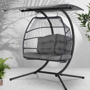 Grey two seater egg chair with canopy in a room with plants