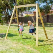 Two girls swinging side by side on the timber swing set