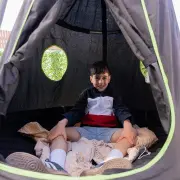Boy sitting cross-legged inside the cocoon on a blanket