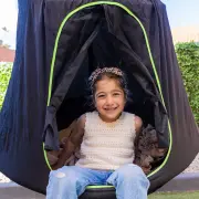 Girl sitting in the doorway of the black cocoon tent swing with a blanket