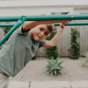Boy leaning out from the green steel monkey bars
