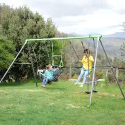 Two children on the nest swing and the swing seat of the steel swing set, on a lawn