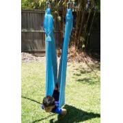 Boy sitting in the teal wrap swing on the swing set stand, front view