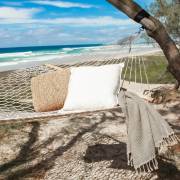 Natural rope hammock on a beach with a cushion and a basket