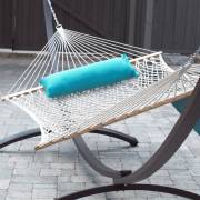 Natural rope hammock with a turquoise bolster on a hammock stand on a patio