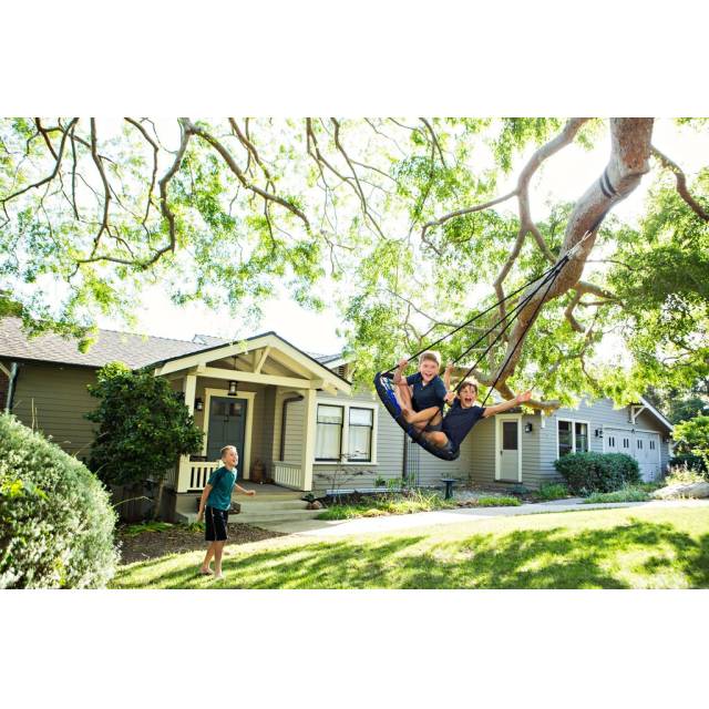 Child swinging on a nest swing hung from a tree branch with the tree straps