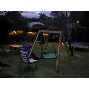 Customer photo of the timber web swing set in a backyard at dusk, under string lights