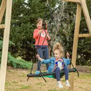 Two girls on the web swing, one standing and one sitting