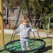 Toddler standing in the web swing holding the ropes