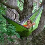 Woman waving from the green parachute hammock hung in a tree