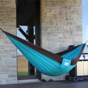 Turquoise parachute hammock hung on a deck beside a stone house