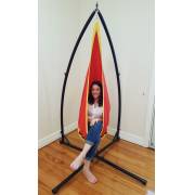 Woman sitting inside the red and yellow pod chair on the X stand, side view