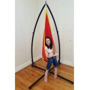 Woman sitting in the red and yellow pod chair on the X stand