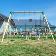 Children on the two belt swings and the trapeze in a backyard