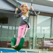Girl standing on a green belt swing, holding the coated chains