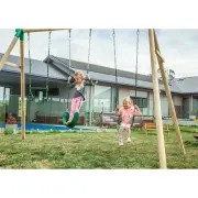 Two girls on the two belt swings beside the trapeze, in front of a house