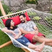 Couple lying in the white rope hammock with a red pillow