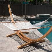 White rope hammock on a wooden arc stand beside a pool