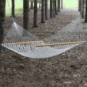 White rope hammock hung between trees in a wood