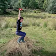 Boy holding the trolley handles and riding the flying fox across a paddock