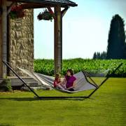 Woman and child in a rope spreader bar hammock on the three beam stand on a lawn
